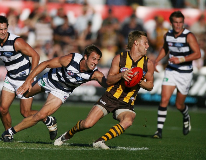 Hawthorn v Geelong. Aurora Stadium, Launceston. Sam Mitchell spins out of trouble and escapes three Cat players in Jimmy Bartel and Joel Corey.